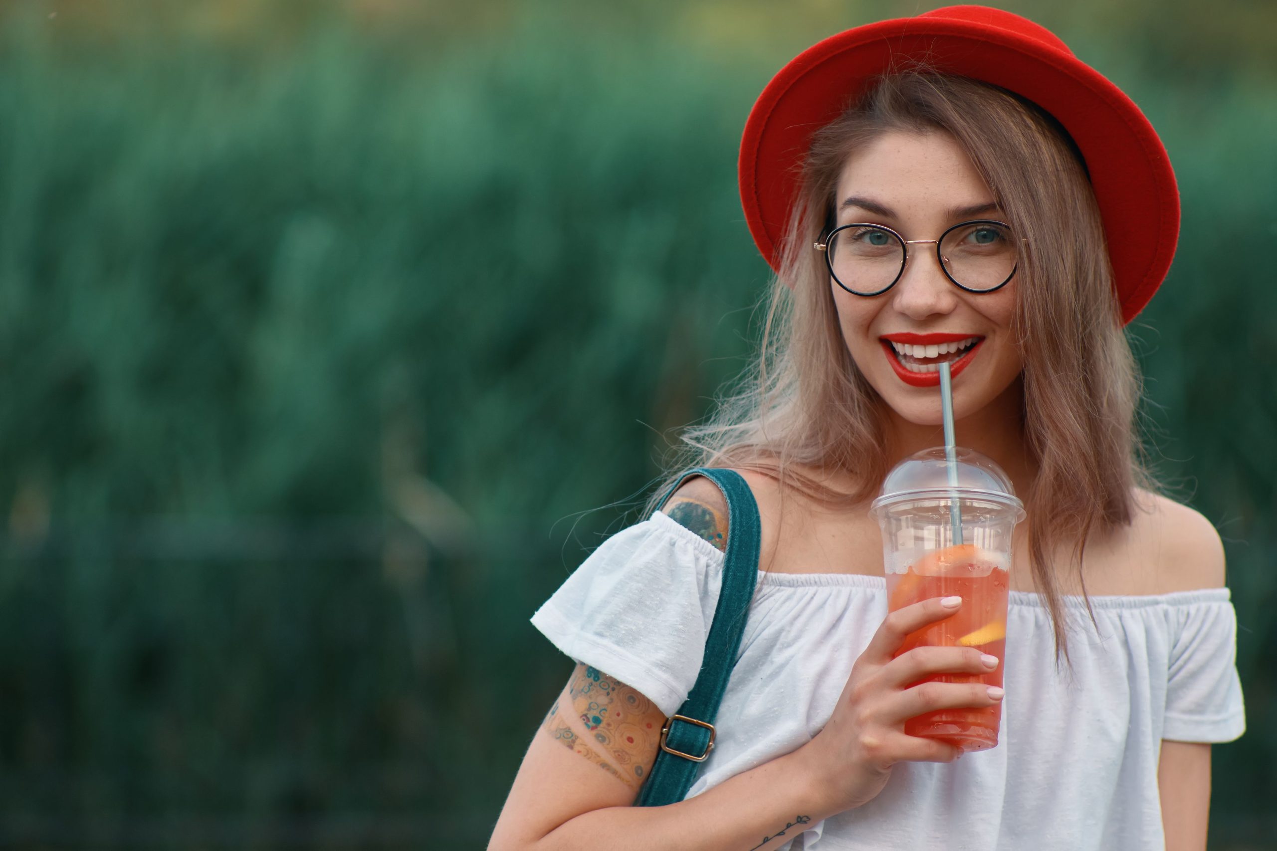 young stylish woman having refreshing drink while walking
