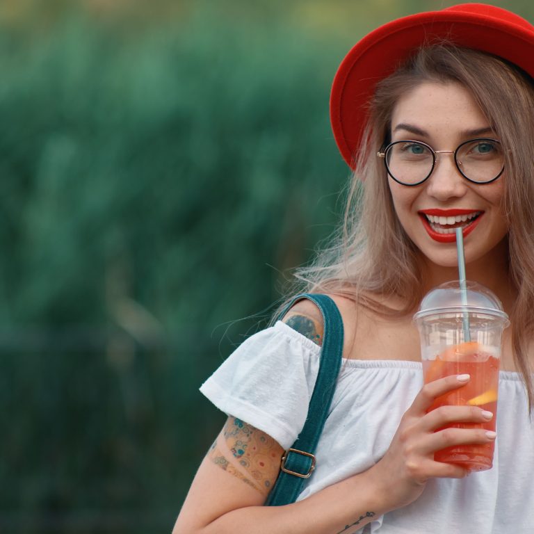 young stylish woman having refreshing drink while walking